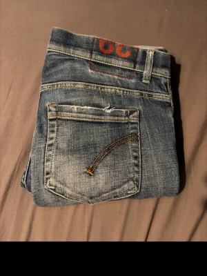 Blå jeans från George - Säljer ett par blå skinny fit jeans från George med slitna detaljer och snygga kontrastsömmar på bakfickan. Klassisk femficksmodell i denim med en cool tvättad look. Perfekta för dig som gillar en smal passform och streetstil. Litet hål