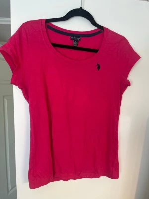 Rosa t-shirt från U.S. Polo Assn - ÄKTA!! Snygg rosa t-shirt från U.S. Polo Assn med klassisk rund halsringning och mörkblå/svart broderad logga på bröstet. T-shirten är kortärmad och har en normal passform. Jag bär oftast S/M!💗