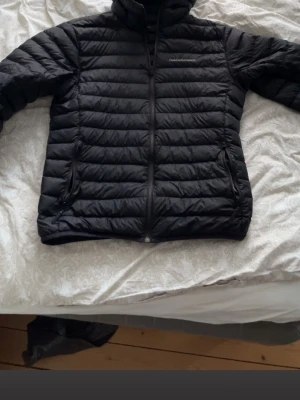 Svart dunjacka Peak Performance L - Snygg svart dunjacka från Peak Performance i storlek L. Jackan har quiltad design, dragkedja framtill och hög krage. Perfekt för kyliga dagar och enkel att matcha med olika outfits. 9/10 skick! 