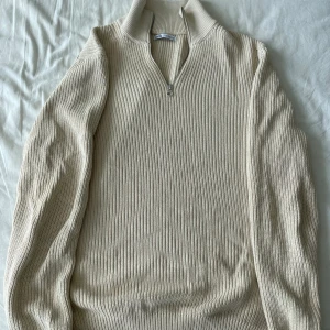 Beige stickad tröja från Zara - Säljer en snygg beige half-zip från Zara. Tröjan har en dragkedja vid halsen och är perfekt för både höst och vinter. Half-zipen är långärmad och i nyskick, supermysig och stilren! Frågor? Skriv!