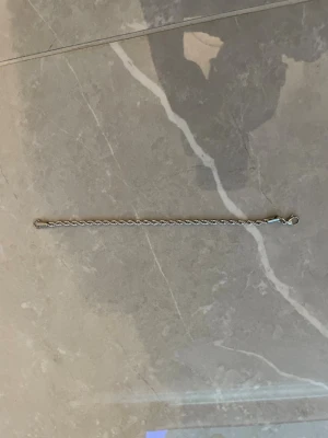 Tunt silverfärgat kedjearmband - Stilrent armband i tunn silverfärgad kedja med karbinlås. Perfekt för dig som gillar minimalistiska smycken och vill ha något diskret men ändå snyggt runt handleden. Passar till de flesta stilar och är lätt att kombinera med andra armband.