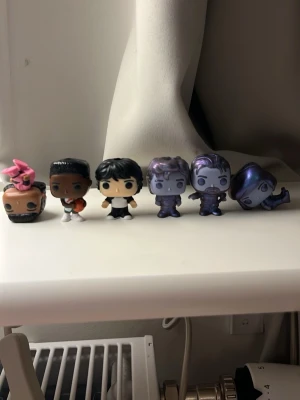 Kinder joy!. funko pop. Stranger things  - Säljer en samling med 6 Funko Pop minifigurer i olika färger och stilar. Figurerna är gjorda av plast och har unika detaljer, bland annat en med rosa kläder och hårsnodd, samt flera med metallic-lila och grå nyanser. Perfekt för dig som gillar samlarfigurer och popkultur.