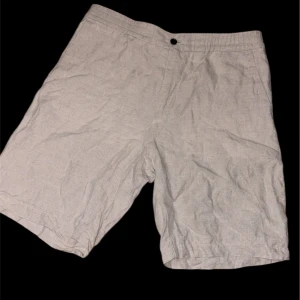 Beige linneshorts från J.Lindeberg - Snygga beige shorts från J.Lindeberg i luftig linnemix. Klassisk rak passform med knappstängning fram och diskreta fickor bak. Perfekta för varma dagar när du vill ha en clean och chill look.