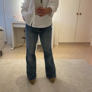 Blå bootcut jeans  - Säljer ett par blå bootcut jeans från Creator med små ljusa ränder. Köpta på en secondhand butik och har en avslappnad stil. Midjan går att vika ner för att få jeansen mer lågmidjade. Innerbenslängden är 75 cm och rakt över midjan är den ca 35 cm. Skulle säga att de passar s/m