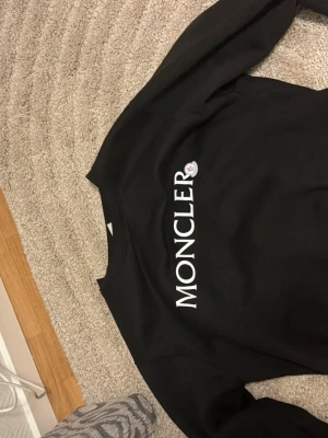 Svart sweatshirt - Säljer en svart sweatshirt med stor vit logga tryckt på bröstet. Tröjan har rund halsringning och långa ärmar. Perfekt för dig som gillar stilrena och exklusiva plagg.