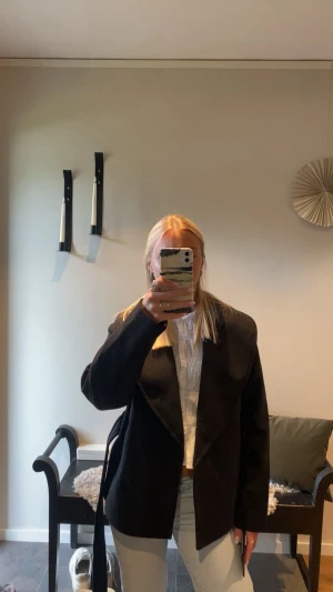 Svart kappa med skärp - Stilren svart kappa med bred krage och knytband i midjan. Kappan har en rak passform och är perfekt för dig som vill ha en klassisk look. Passar snyggt till både jeans och sneakers. Materialet ser ut att vara mjukt och följsamt.