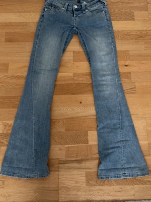 Ljusblå bootcut jeans med fickdetaljer - Säljer mina blåa true religion jeans i storlek 23, pågrund av att de är i fel storlek för mig. Lite smutsiga nertill men de tvättas självklart innan försäljning. Kontakta mig för fler frågor!