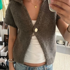 Brun stickad kofta från Zara - Säljer en mysig brun stickad kofta från Zara med korta ärmar och en stor knapp framtill. Bara använd fåtal gånger.