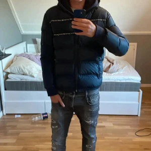 Mörkblå pufferjacka Tommy Hilfiger - Mörkblå dunjacka från Tommy hilfiger, mycket varm och skön så passande nu till höst/vinter. Lite problem med zippern ibland, troligtvis går det att fixa men har ej orkat försöka. Annars i ett ok skick! Har sett liknande säljas för runt 5 tusen kr. Storlek 176, passar som S. Skriv vid intresse, pris går naturligtvis att diskuteras.