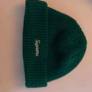 Grön ribbstickad mössa från Supreme - Säljer en grön Supreme mössa i stickad modell. Klassisk design med uppvikt kant och Supreme-loggan framtill. Bekväm och varm, perfekt för höst och vinter. Mössan är aldrig använd då jag använde den som en samling pryl eftersom att jag var besatt av supreme förut. Mössan är köpt i USA (äkta) på en supreme butik 2020 (limited edition)