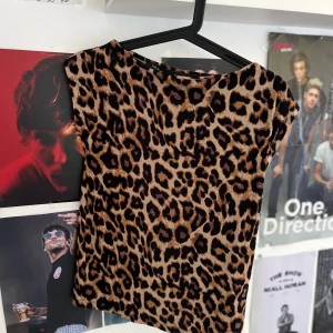 Leopardmönstrad topp från Black Label - Säljer en snygg leopardmönstrad topp från The Black Label Collection i storlek S. Toppen har en rund hals och är ärmlös, med beige och bruna toner i mönstret. Perfekt för dig som vill sticka ut med ett djuriskt print.