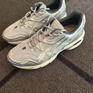 Asics GEL-1090 skor - Snygga Asics GEL sneakers i ljusblå. Ovandelen är i mesh och syntet, vilket ger en sportig vibe och bra andningsförmåga. Klassisk snörning och rund tå. Perfekta för dig som gillar stilrena och bekväma skor.