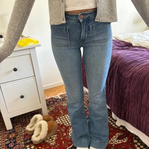 Blå bootcut jeans från Wrangler - Säljer ett par klassiska blå bootcut jeans från Wrangler med hög midja och råa kanter nertill. Jeansen har framfickor, bakfickor med Wrangler-logga och är tillverkade i mjukt denim. 