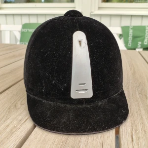 Svart ridhjälm strl 54 - Snygg svart ridhjälm från Kylin med sammetsyta och silverfärgad detalj. Fint skick men använd, har aldrig trillat av med eller slått i på något sätt. Kan gå ner i pris vid snabb affär☺️
