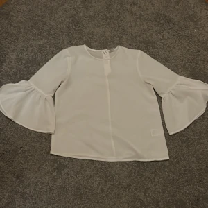 Vit blus från Lindex - Säljer en vit blus som använts en eller två gånger som fintröja. Som man ser i bilderna så har den knappar baktill som spänner åt den lite extra. Precis som ny.