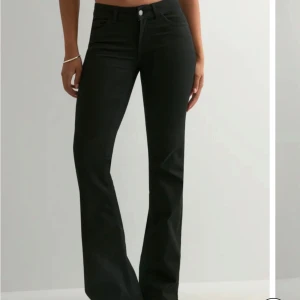 Svarta bootcut jeans med låg midja - Snygga svarta jeans med bootcut passform och låg midja. Klassisk femficksmodell med knapp och dragkedja framtill. Jeansen har stilrena bakfickor med diskret broderad detalj.