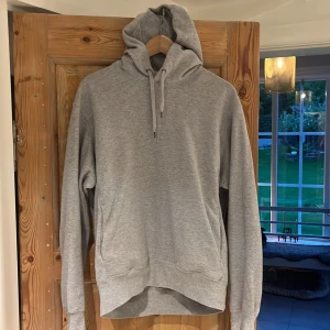 Grå hoodie från Uniqlo med huva - Säljer en stilren grå hoodie från Uniqlo i storlek M. Tröjan har huva. Perfekt för chill dagar eller när du vill ha en enkel och clean look. Använts ett fåtal gånger