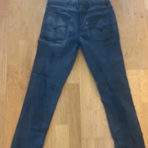 Mörkgråa Levi's jeans slim fit  - Säljer ett par mörkgråa Levi's jeans med klassisk femficksdesign och skinny passform. Jeansen har en diskret tvättad look och är tillverkade i mjukt denimtyg. Perfekta för dig som gillar en smal siluett och stilren look. Säljer jeansen för att de är för små för mig. Storlek 176 cm. Knappt använda. 