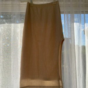 Beige kjol med slits - Snygg beige kjol med strukturerat tyg och en liten slits på sidan. Kjolen är fodrad och har en rak passform som känns både trendig och enkel att styla. Perfekt för dig som gillar stilrena plagg med det lilla extra.