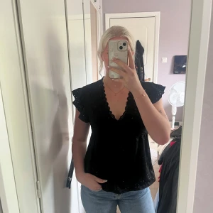 Svart blus med volangärm och spets - Säljer en svart blus med v-ringning och spetskant. Blusen har korta volangärmar och ett luftigt fall. Knappt använd. Passar både S och M. Fråga gärna vid fundering.☺️