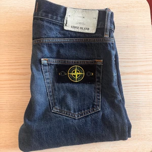 Stone Island blå jeans W29 - Snygga blå jeans från Stone Island med klassisk femficksdesign och ikonisk kompasspatch på bakfickan. Jeansen har raka ben. W29L34 i storlek. Priset är inte hugget i sten