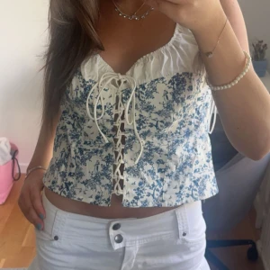 Vit och blå korsett med snörning INTEESSE!!! - Superfin korsett-topp i vitt med blått blommönster och snygg snörning framtill. Osäker om ja vill sälja så skriv isåfall!!!