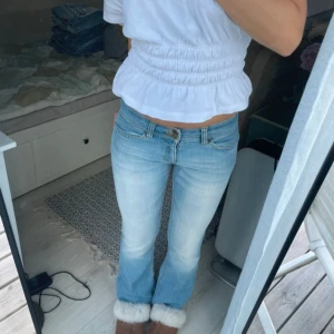 Ljusblå bootcut jeans med låg midja - Säljer ett par ljusblå jeans med bootcut och låg midja. Jeansen har klassiska fem fickor, snygga sömmar på bakfickorna och dubbla knappar i midjan. Tillverkade i jeansmaterial och perfekta för dig som gillar en avslappnad men trendig look.