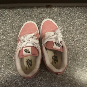 Rosa Vans Old Skool sneakers - Säljer ett par klassiska Vans Old Skool sneakers i en snygg rosa färg med vita detaljer och vit sula. Skorna har snörning och är tillverkade i mocka och textil. Perfekta för dig som vill ha en cool och avslappnad stil.