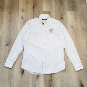 BALMAIN skjorta -  🩶 Vit BALMAIN skjorta 🩶 Elegant skjorta av Balmain Paris i 100% bomull med unik brodering och knappslå. Inga större tecken på användning.  🩵 Färg: Vit 💙 Storlek: M - 38/39 💠 Mått: • Bröst: ~55cm • Längd: ~74cm  🔹 Priset är inte hugget i sten!!