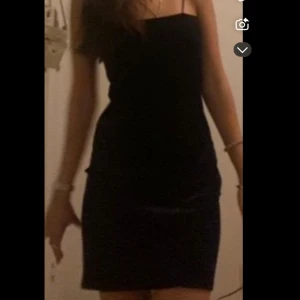 Svart tight kort klänning med smala band - En svart, figurnära kort klänning med tunna axelband och rak halsringning. Enkel och stilren design som ger en snygg siluett. Perfekt för dig som gillar minimalistisk stil och vill ha en klassisk look.