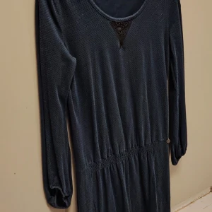 House of Lola Mörkblå långärmad klänning - Supersnygg mörkblå klänning från Odd Molly med lång ärm och rund halsringning. Klänningen har ett diskret prickigt mönster, elastisk midja och en liten spetsdetalj vid halsen. Materialet är mjukt och känns lyxigt mot huden. Liten metallbricka med Odd Molly-logga vid midjan.