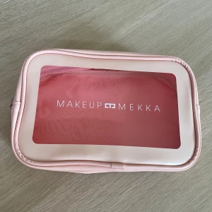 Rosa necessär från Makeup Mekka - Säljer en söt och praktisk rosa necessär från Makeup Mekka. Väskan har ett genomskinligt fönster på framsidan och dragkedja runt om. Perfekt för att organisera smink eller småprylar. Tillverkad i syntetmaterial med mjuk känsla.