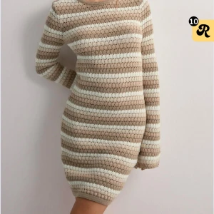 Randig stickad klänning - Supermysig stickad klänning med beige och vita ränder. Modellen är kort med långärmade ärmar och har en slim passform som sitter snyggt på kroppen. Perfekt för dig som gillar en chill och trendig look. Materialet är stickat och känns mjukt mot huden.