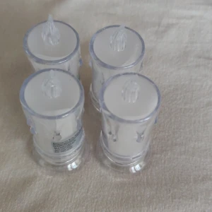 LED värmeljus (4-pack) - Fyra batteridrivna LED värmeljus med flammande effekt. Genomskinlig design med vit insida, på/av-knapp undertill. Perfekt för stämningsbelysning utan brandrisk. Helt ny.