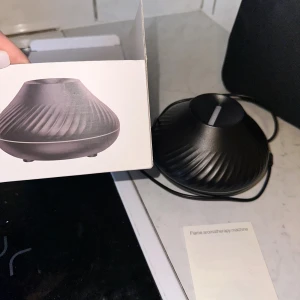 Flame Aromatherapy Machine  - Modern aromaterapimaskin med flammande effekt, modell CD705. USB-driven, svart design med elegant mönster. Komplett med originalkartong och manual. Produkten är i nyskick utan synligt slitage eller defekter. Perfekt för hemmet eller kontoret. 🎁