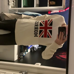 Vit stickad tröja med märke på bröstet Morris - Vit stickad tröja från Morris med Storbritanniens flagga och Morris stavelsen på bröstet. En väldigt varm och skön tjocktröja som passar perfekt för den kalla vintern. Storleken som Står är L men den är mycket mindre och sitter som en M. Säljer eftersom den inte passade mig i storleken.