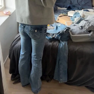 Nelly bootcut jeans  - Säljer ett par ljusblå bootcut jeans med snygga slitningar nertill och coola fickdetaljer bak. Jeansen har låg midja och klassisk femficksdesign. Perfekta för dig som gillar en avslappnad och trendig look.