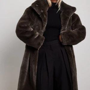 Mörkbrun pälsjacka med oversized passform - Säljer denna fluffiga och långa pälsjacka med bred krage. Jackan är helfärgad mörkbrun och är både varm och tjock. Använd ett fåtal gånger 