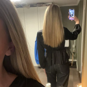 Svart omlottblus med knyt i midjan - Säljer en svart omlottblus med knyt i midjan och långa ärmar. Blusen har en v-ringad skärning och är tillverkad i ett glansigt, mjukt material som ger en lyxig känsla. Perfekt att styla med jeans eller kjol för en trendig look.