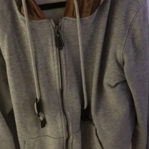  Burberry tracksuit/sett - Grå sett från Burberry med klassiska rutiga detaljer i brunt och beige vid fickorna. Settet har en avslappnad passform och är tillverkade i mjukt bomullsmaterial. Perfekta för en chill och stilren look.