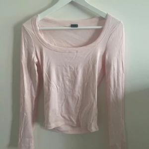 Ljusrosa ribbad topp Gina Tricot - Supersöt ljusrosa långärmad topp från Gina Tricot. Är helt ny och aldrig använd, tyvärr har jag klippt bort prislappen. Modellen är ribbad med rundad halsringning och sitter snyggt figurnära. Perfekt att styla med jeans eller kjol för en enkel och fräsch look.