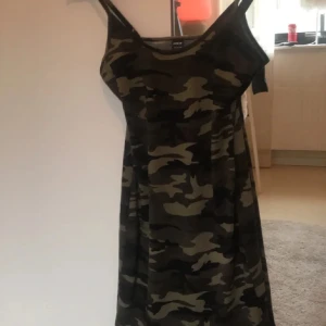 Camouflage kortklänning med slits - Säljer en cool kortklänning med camouflage-mönster i gröna och bruna toner. Klänningen har smala axelband och en liten slits på sidan för extra edge. Perfekt för dig som gillar streetstyle och vill sticka ut.