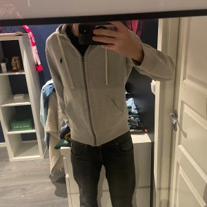 Grå Zip hoodie från Ralph lauren - En snygg zip hoodie som inte tillverkas längre. Den är färgen grå och storleken S han på bilden är 178 cm. 