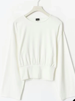 Vit croppad sweatshirt med vida ärmar - Snygg vit croppad sweatshirt från NA-KD med bred resår i midjan och vida långa ärmar. Tröjan har rund halsringning och är tillverkad i mjukt material som känns skönt mot huden. Perfekt för en avslappnad och trendig look.