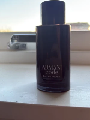 Armani Code Eau de Parfum 50ml kvar - Säljer en stilren parfymflaska från Armani Code Eau de Parfum. Flaskan är svart och cylinderformad med elegant minimalistisk design. Perfekt för dig som gillar exklusiva dofter och vill ha en snygg parfym på hyllan.