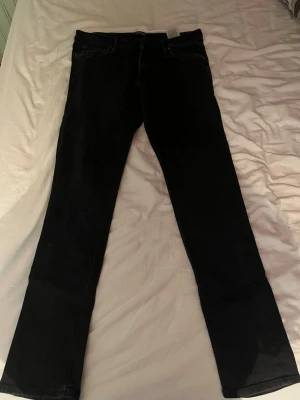 Svarta raka jeans - Säljer ett par svarta jeans med rak passform och klassisk femficksdesign. Jeansen har normal midja och är tillverkade i ett mjukt denimtyg som ger en snygg och stilren look. Perfekta till en avslappnad outfit.