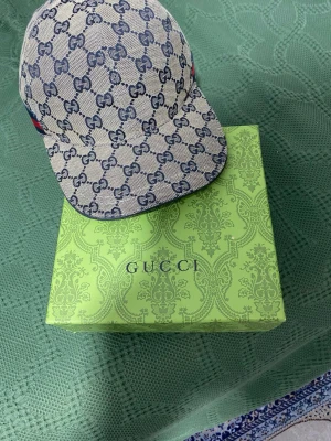 Gucci keps  - Snygg keps från Gucci i beige canvas med klassiskt blått GG-monogram över hela kepsen. Baksidan har ett blått och rött band samt justerbart spänne. Perfekt accessoar för att lyfta din stil med lyxig känsla.
