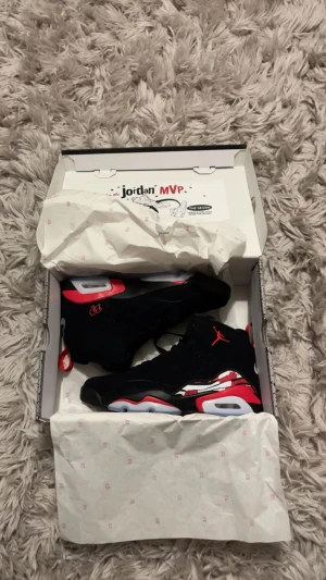 Nike Jordan MVP svart/röd sneakers - Nike Jordan MVP sneakers i svart och rött med coola detaljer och Jumpman-logga. Skorna har snörning, hög siluett och en platt sula med genomskinliga partier. Materialet är mocka och syntet, med grafiska mönster på sidan och 23-brodyr. Perfekt för dig som vill sticka ut. Aldrig använda endast testade, fick i present. 