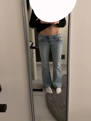 Ljusblå bootcut jeans  - Säljer ett par ljusblå bootcut jeans med låg midja från Gina Tricot. Jeansen har en avslappnad passform och är tillverkade i denim. 