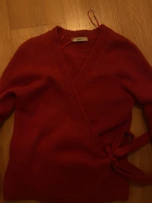 Röd omlottkofta från Gina Tricot - Säljer en röd stickad omlottkofta från Gina Tricot. Koftan har långa ärmar, ribbstickade kanter och knyts i sidan för en snygg passform. Köptes för 400! Pris kan diskuteras.